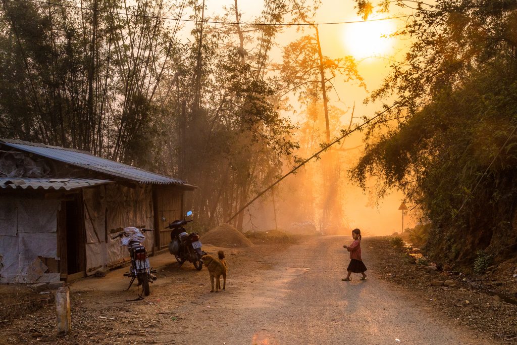 A young girl crosses the road from Sapa to her village during sunset in Vietnam