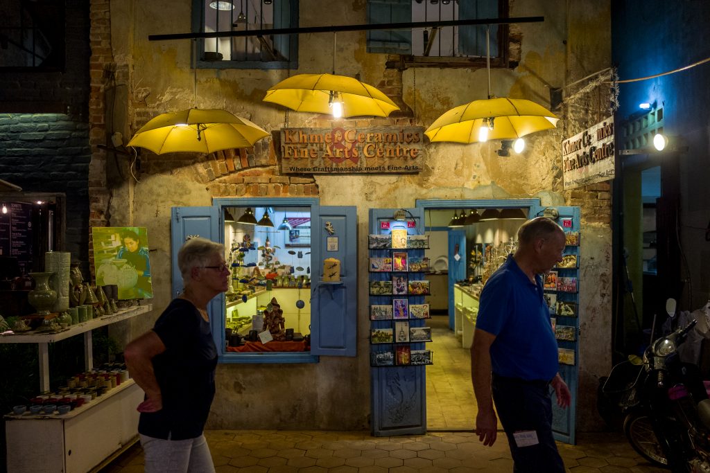 A tourist couple walks past one of the many shops in Cambodia