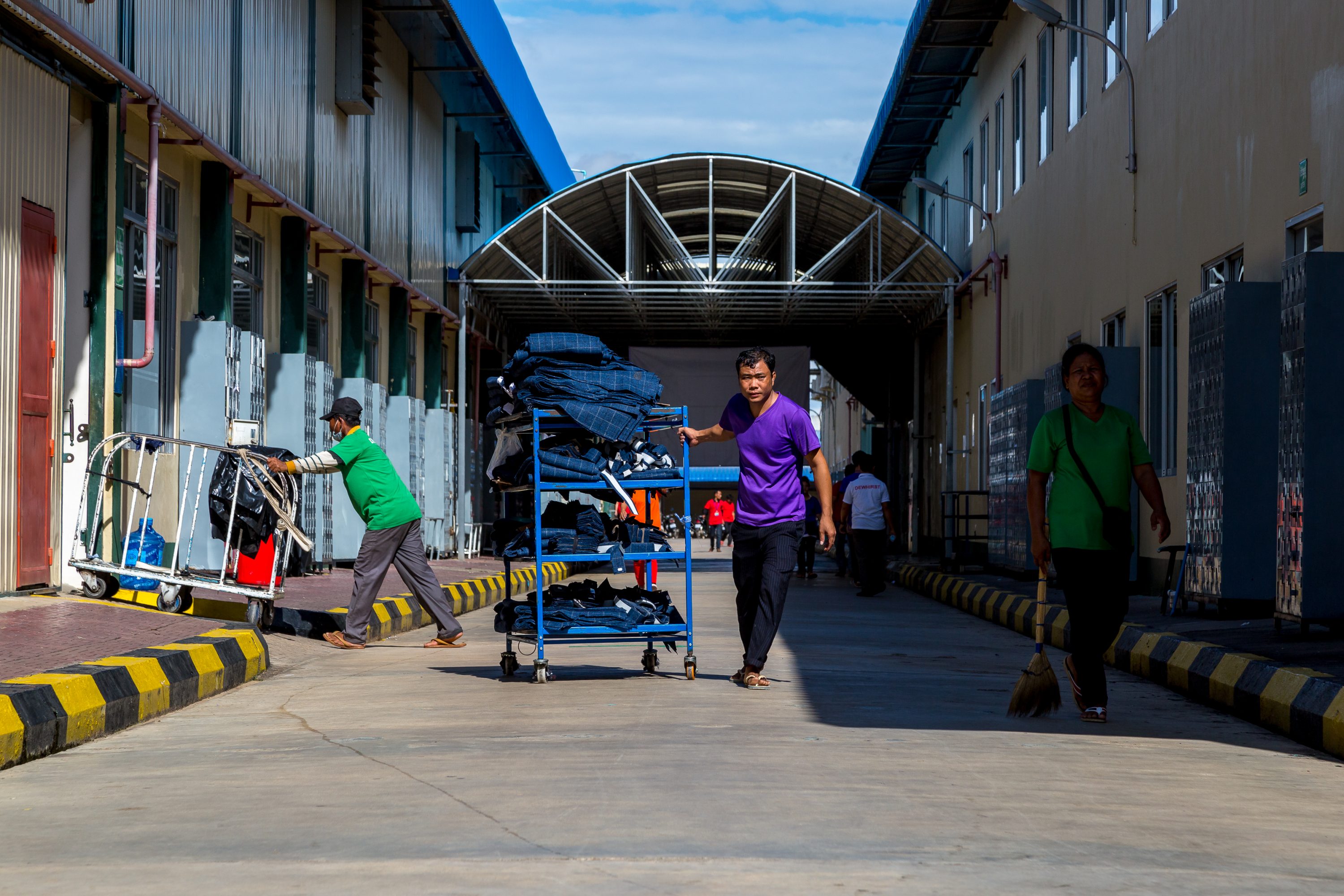 A garment worker carries a cart full of textiles in Cambodia