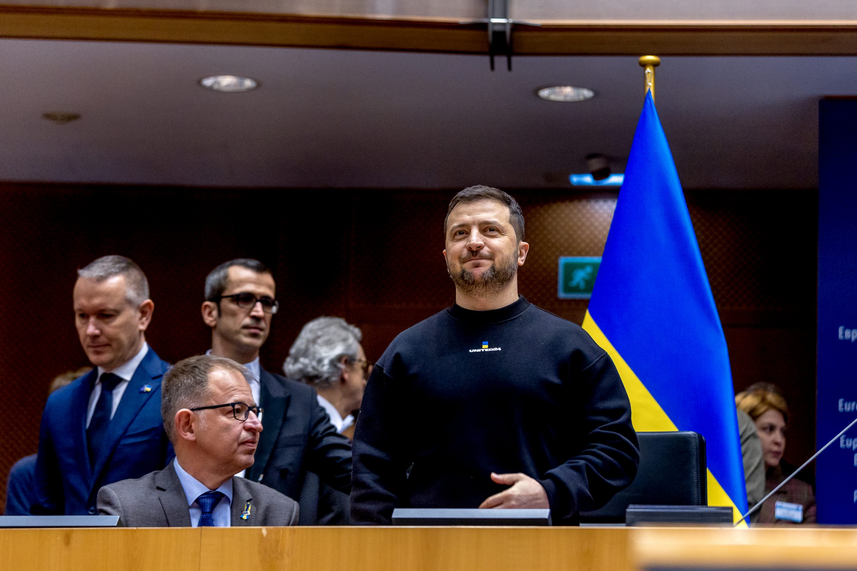 Ukrainian President Volodymyr Zelensky stands as he receives the applause in Brussels