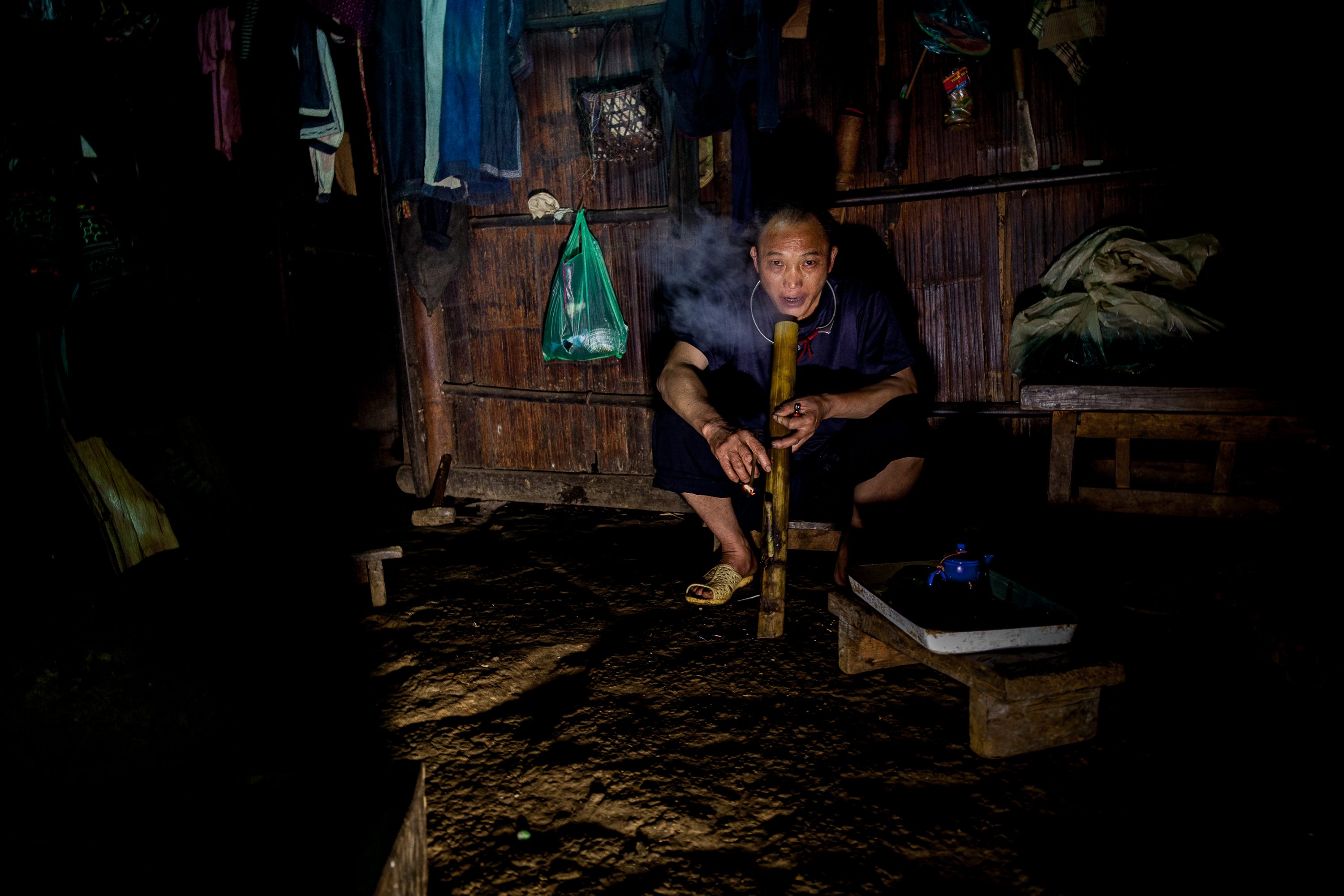 A shaman smokes tobacco from a bamboo pipe in Vietnam