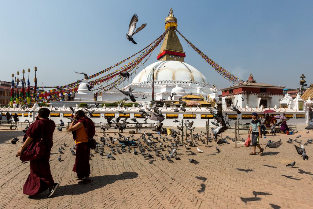 Buddhist monks walk in Boudhanath stupa in Nepal